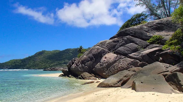 Gray Black Rock divide the sections of beach on the coast of the seychelles in this beautiful bathing bays with turquoise water, lush palm trees, white sand beaches and blue sky