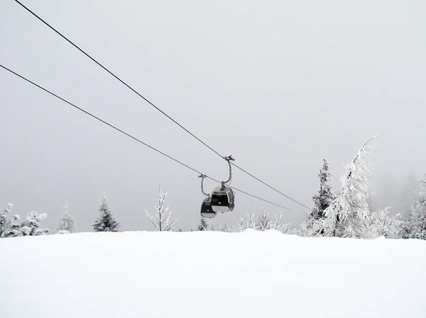 スキーのケーブルカー雪に覆われた山の上の上霧の中から現れるし 谷に道にはケーブルカーのキャビンを満たしています — ストック写真