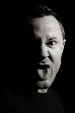 Dilinizi çıkarın. 30 ile 40 yıl arasında bir adam kafa portresi. Yüzünü siyah beyaz yumuşak düşük anahtar tasarım dilini gösterir görünüm doğrudan kameraya doğru gider, göz geniş açık ve yüzü kızgın ya da komik