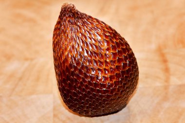 Snake fruit Salak in detail on a wooden plate. You see the fine grain and structure of the skin of this ripe fruit, which looks like a snake. clipart
