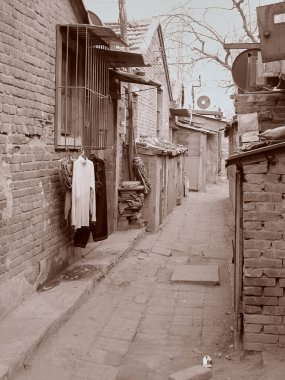 Sepiatonung Pekin'de işçi çeyreğinde boş sokaklar ve asılı giysiler ile