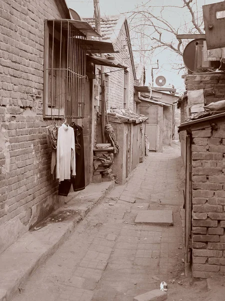 Sepiatonung Pekin'de işçi çeyreğinde boş sokaklar ve asılı giysiler ile