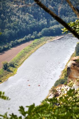 Elbe Nehri 'nin kaleden görünüşü, yeşil ormanların ortasında ve sudaki küçük teknelerle.
