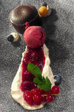 Çikolatalı pasta, kırmızı çilekli dondurma, vanilyalı krema ve çeşitli meyveli taş tabaklar.