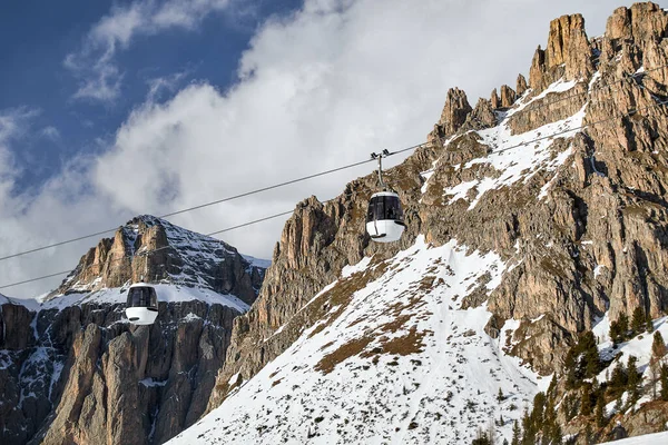 two white ski lift cabins in front of the typical rugged, rugged majestic rocks in the Italian Dolomites at the sellaronda ski area