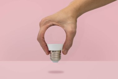 Pembe, izole bir ampul şekli tutan el dk