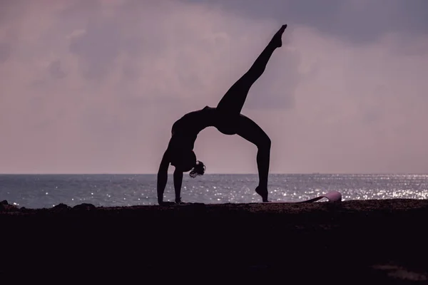 Silueta de mujer practicando yoga en la playa —  Fotos de Stock