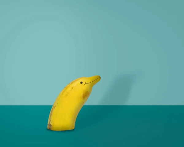 Креативні фрукти, банан, як дельфін на синьому фоні — стокове фото