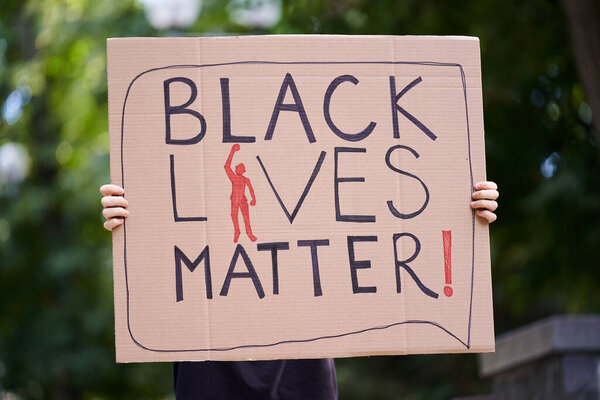 Kiev, Ukraine - July 31 2020: Black Lives Matter poster with man raising hand in hands Stop racism concept. Black Lives Matter protest sign. Action against discrimination by skin color.