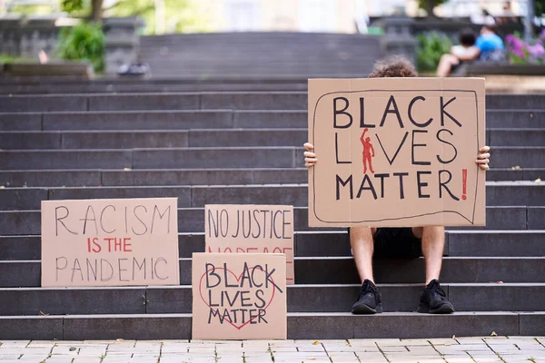 Kiev, Ucrania - 31 de julio de 2020: Black Lives Matter posters near man sitting on the stairs. Detener el concepto de racismo. La vida de los negros importa signo de protesta. Acción contra la discriminación por color de piel. —  Fotos de Stock