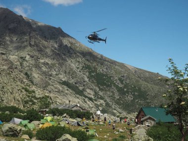 Fransa, Corsica, Corsician Alps, 19 Haziran 2017: helikopter temini için dağ kampı sığınma de Pietra Piana ünlü yürüyüş üzerinde vazgeçtiklerini iz Gr20, kayalar, çadır, ağaç ve mavi gökyüzü arka plan