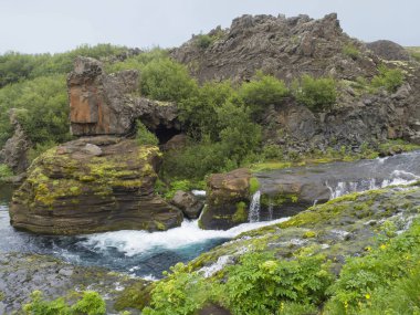 Güzel vadi Gjain ile renkli lav kayaları, yeşil bitki örtüsü ve mavi su akışı cascade south Iceland'deki / daki