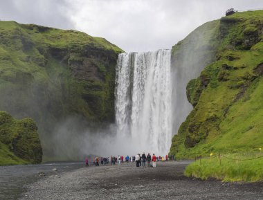 Güney İzlanda Skogar grup renkli giyinmiş turist insan ile güzel Skogafoss şelale