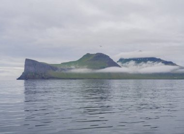 Batı fjords güzel Hornbjarg kayalıklardan okyanusta doğal görünümünden, doğa rezerv Hornstrandir İzlanda, bulutlu gökyüzü arka plan mavi deniz ve yeşil kar yamalı Dağları ile