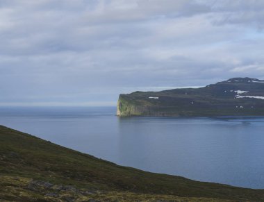Batı fjords güzel kar yamalı kayalıklardan okyanusta doğal görünümünden, doğa rezerv Hornstrandir İzlanda, mavi deniz ve bulutlu gökyüzü arka plan, altın saat ışık