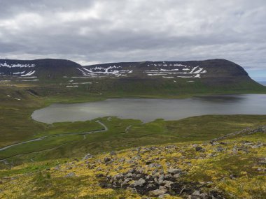 Kuzey yaz manzara, güzel kar kayalıklarla ve fljotsvatn Gölü Hornstrandir, Batı fjords İzlanda, içinde Fljotavik Cove Nehri akış, yeşil çim çayır, moody gökyüzü arka plan ile kaplı