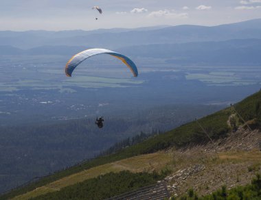 İki paraşütler bir güneşli yaz gününde bir dağ Vadisi uçmak. Mavi ve turuncu uçurtma tatra Dağları Slovakya yaz güneşli gün kiting