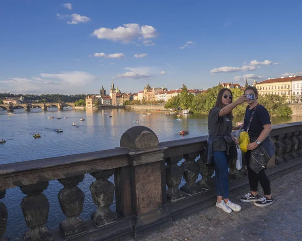 República Checa, Praga, 8 de septiembre de 2018: dos jóvenes, amigas adolescentes tomando una foto selfie en el Puente de la Legión con vista al Castillo de Vltava Praga y la Ciudad Vieja, luz de hora dorada, día soleado — Foto de Stock