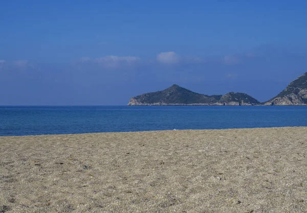 Zand en kiezels strand en turquoise zee kust bij Agios Georgios Pagon op het eiland Corfu, Griekenland met uitzicht op porto timony bay — Stockfoto