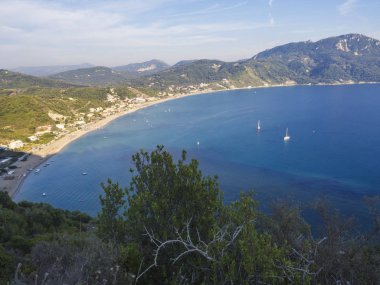 Agios Georgios Pagon kum Beach yeşil tepeler ve yelkenli gemi, Corfu Island, Yunanistan, güneşli gün mavi gökyüzü ile panoramik görünüm.