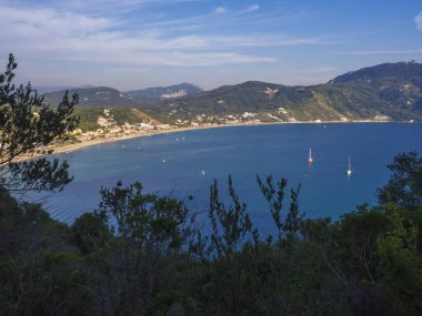 Agios Georgios Pagon kum Beach yeşil tepeler ve yelkenli gemi, Corfu Island, Yunanistan, güneşli gün mavi gökyüzü ile panoramik görünüm.