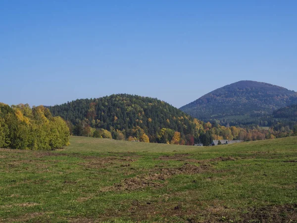 Prato verde con autunno foresta colorata e alberi e colline prima del tramonto paesaggio in luzicke lusitian hory montagna — Foto Stock