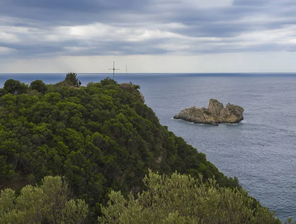 Uitkijkpunt met Kruis en cllifs, bomen en groene heuvel aan de baai van Paleokastritsa, zomer bewolkte hemel, Corfu, Crete, Griekenland — Stockfoto