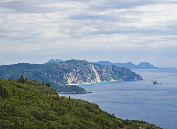 Kijk op de heuvel van cllifs, bos en groen en turquoise blauwe zee bij Paleokastritsa bay, zomer bewolkte hemel, Corfu, Crete, Griekenland — Stockfoto