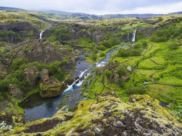 Hermoso valle de Gjain con rocas de lava de colores, musgo verde exuberante y vegetación y agua azul con cascadas y cascada en el sur de Islandia —  Fotos de Stock