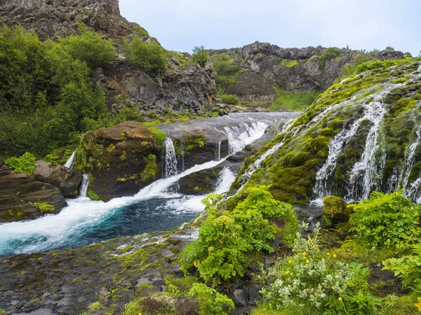 Hermoso valle de Gjain con rocas de lava de colores, musgo verde exuberante y vegetación y agua azul con cascadas y cascada en el sur de Islandia —  Fotos de Stock