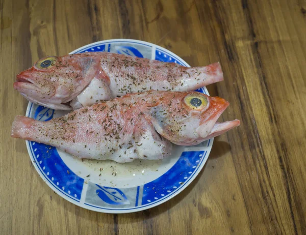 Two close up marinated Atlantic Redfish with rosemary and lemon on blue plate on wooden desk table — Stock Photo, Image