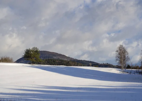 Champ d'hiver et forêt campagne paysage enneigé avec arbres, colline et siège haut en bois dans la montagne luzicke hory — Photo