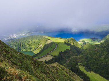 Çarpıcı görünümü volkanik göller üzerinde. Yeşil Lagoa de Santiago ve mavi Lagoa Azul'la Sete Cidades Köyü, kısmen sis sis ve bulutlar tarafından kapsanan. Sao Miguel Azores, Portekiz