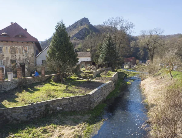 View on village with rver and rock cliff Svaty Jan pod Skalou, Beroun, Central Bohemian Region, Czech Republic, Famous pilgrimage place, spring sunny day, blue sky — Stock Photo, Image