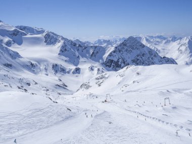 Kayak merkezi Stubai Gletscher, Stubaital, Tyrol, Avusturya Alpleri 'nde kar kaplı dağ yamaçları ve kayakçılarla dolu kış manzarası.