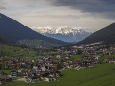Bahar dağ kırsal manzara. Innsbruck yakınlarındaki Stubaital Stubai Vadisi'nin manzarası, Neder köyü ile Avusturya, yeşil çayır, orman, karla kaplı alpen dağ zirveleri, akşam dramatik bulutlar ve