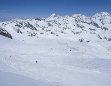 Kayak merkezi Stubai Gletscher, Stubaital, Tyrol, Avusturya Alpleri 'nde kar kaplı dağ yamaçları ve kayakçılarla dolu kış manzarası.