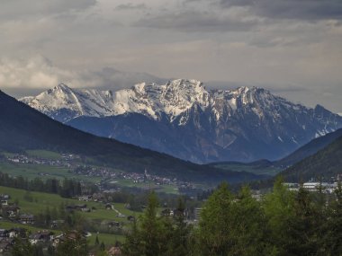 Bahar dağ kırsal manzara. Innsbruck yakınlarındaki Stubaital Stubai Vadisi'nin manzarası, Neder köyü ile Avusturya, yeşil çayır, orman, karla kaplı alpen dağ zirveleri, akşam dramatik bulutlar ve