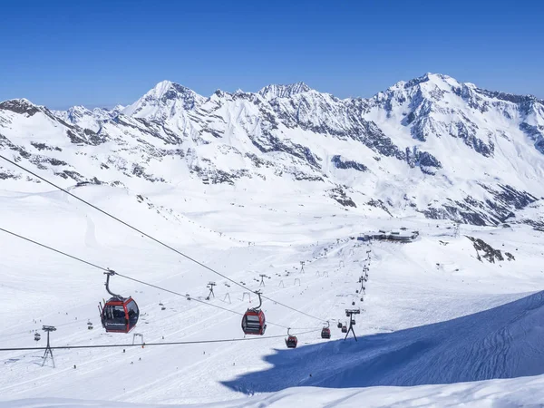 Stubai Glacier, AUSTRIA, May 2, 2019: Snow covered slopes with free rides and pistes and red Cable cars and chair lifts cabin going on the top of Schaufelspitze mountain at Stubai Gletscher ski resort — Stock Photo, Image