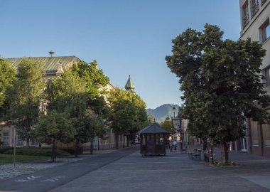 Liptovsky Mikulas, Liptov, Slovakya, 4 Temmuz 2019: Liptovsky Mikulas kentinin merkezindeki Park ve binaların bulunduğu ana meydanda yürüyüş yapan insanlarla görüş. Yaz güneşli gün, altın saat