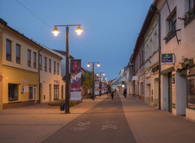 Liptovsky Mikulas, Liptov, Slovakya, 4 Temmuz 2019: sokak ışıkları ve yürüyüş insanlarla Liptovsky Mikulas şehir merkezinde yaya bölgesi ve binalar. Yaz gecesi, mavi saat