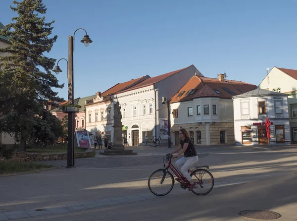 LIPTOVSKY MIKULAS, LIPTOV, ESLOVAQUIA, 4 de julio de 2019: Zona peatonal y edificios en el centro de la ciudad de Liptovsky Mikulas con bicicleta de mujer. Día soleado de verano, hora dorada — Foto de Stock