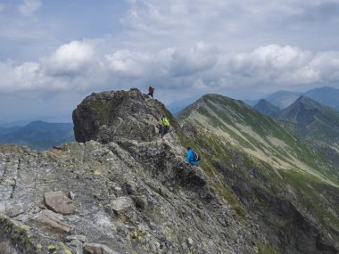 Slovakya, Batı Tatra dağı, Rohacska dolina, Temmuz 2, 2019: Peope rohace dağının sırtında yürüyüş yolu üzerinde tırmanma ostry rohac. Keskin yeşil kayalar, Yaz mavi gökyüzü beyaz bulutlar.