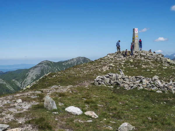 Eslovaquia, montaña occidental de Tatra, 4 de julio de 2019: grupo de excursionistas descansando en la cima del pico Baranec en las montañas occidentales de Tatra con el panorama de Rohace. Sharp verdes montañas con sendero de senderismo en la cresta — Foto de Stock