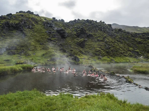 Ісландія, Landmannalaugar, 30 липня, 2019: Група туристів, що розслабляє в природному гаряче джерело в термальних ванн в Landmannalaugar табір, Ісландія. Луг трави, лавові поля і гори в — стокове фото