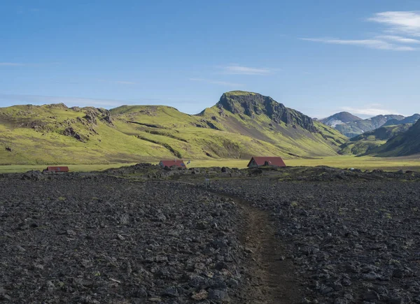 Hvanngil campsite path in lava field and green valley, small houses of hvanngil hut. volcanic mountains volcanic landscape with blue sky, Laugavegur Trail between Emstrur-Botnar and Alftavatn, central — Stockfoto