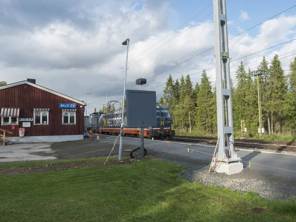 Murjek, Norrbotten, Zweden, Agust 22, 2019: Oude rode bolding van treinstation Murjek met goederentrein naar Kiruna. Zweeds Lapland. Zomer zonnige dag. — Stockfoto