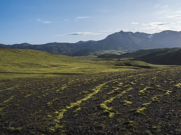 Paisaje volcánico con montañas cubiertas de nieve, colinas verdes y tierra de grava de lava cubierta de musgo exuberante. Reserva Natural de Fjallabak en las Tierras Altas de Islandia — Foto de Stock