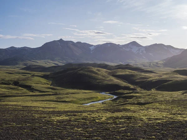 Paisaje volcánico con río azul, montañas cubiertas de nieve, colinas verdes y tierra de grava de lava cubierta de musgo exuberante. Reserva Natural de Fjallabak en las Tierras Altas de Islandia — Foto de Stock