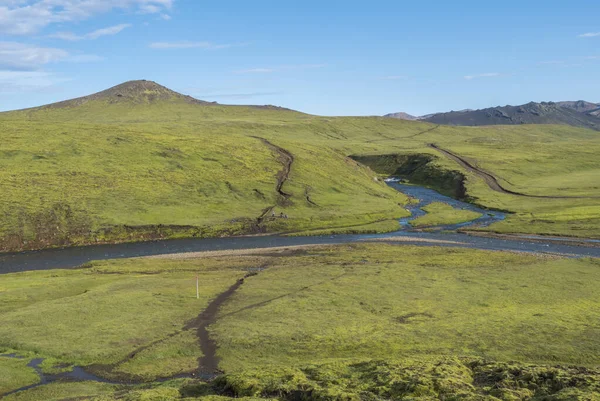 Группа туристов готовится пересечь Голубой речной поток в Лаугавегуре. Пейзаж с зелеными холмами, лугом и пышным мхом. Заповедник Фьяллабак, Исландия. Голубое небо — стоковое фото